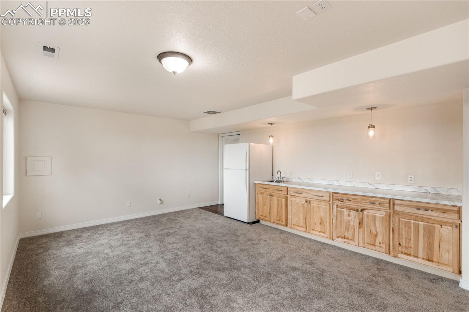 Additional view of bonus room featuring wood cabinetry, counter top with sink and refrigerator.  