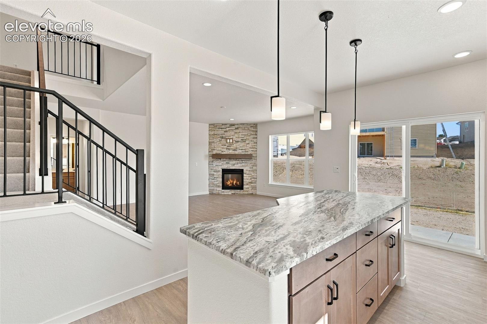 The Kitchen features stainless steel appliances, light maple cabinets with pecan stain, a large kitchen island with quartz countertop, and LVP flooring.