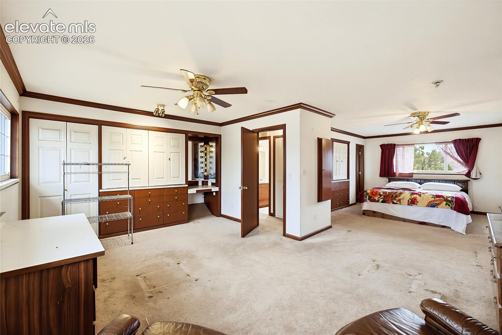Expansive room featuring multiple windows, two ceiling fans, built-in cabinetry with a desk, and wood-finish trim throughout