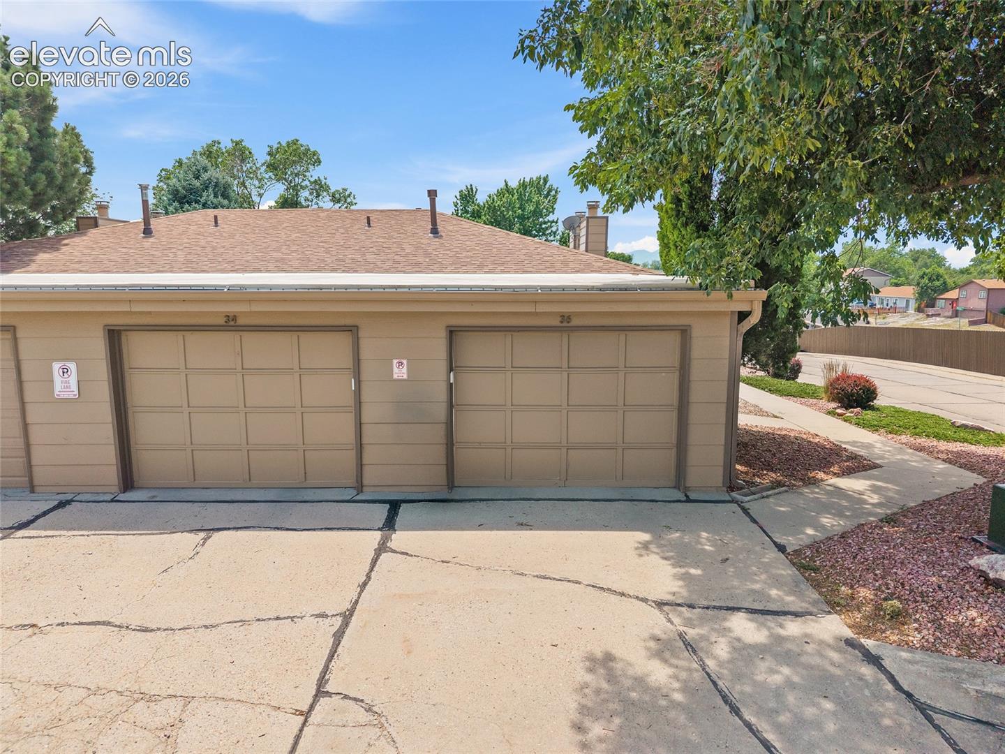 Two single-car garages with panel-style doors and a brown shingled roofline