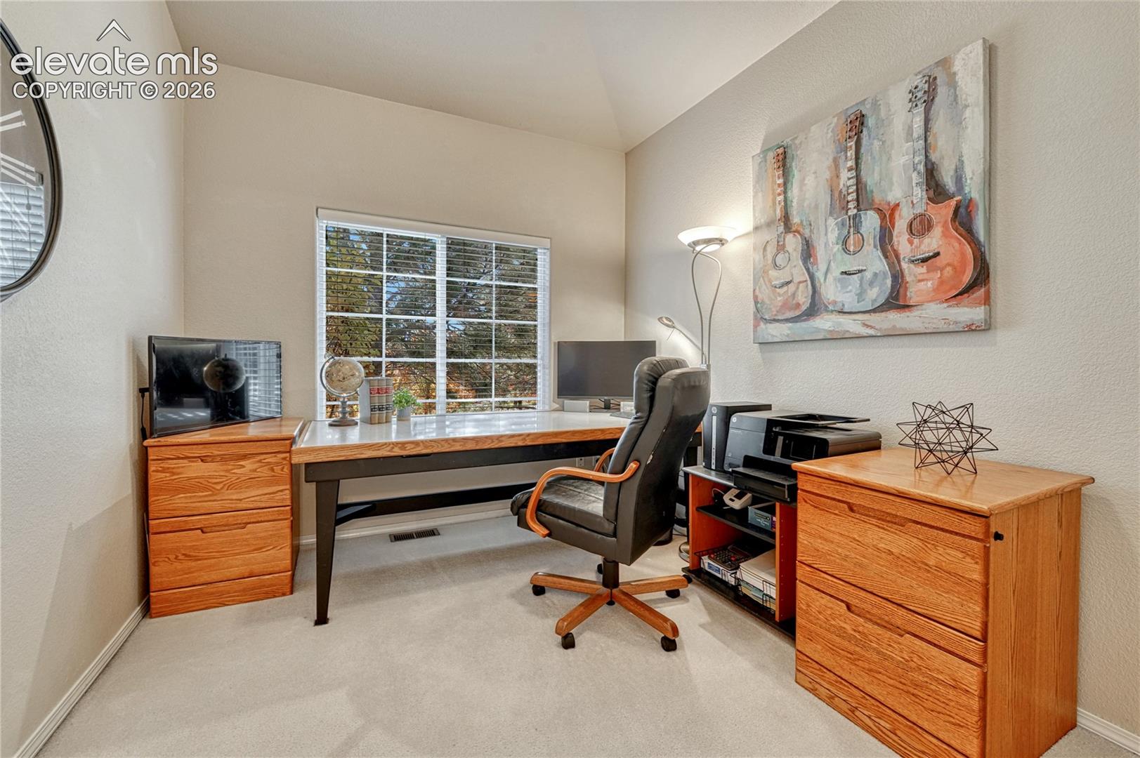 Flexible main-floor second bedroom with vaulted ceilings serves as an ideal home office, den, or guest room
