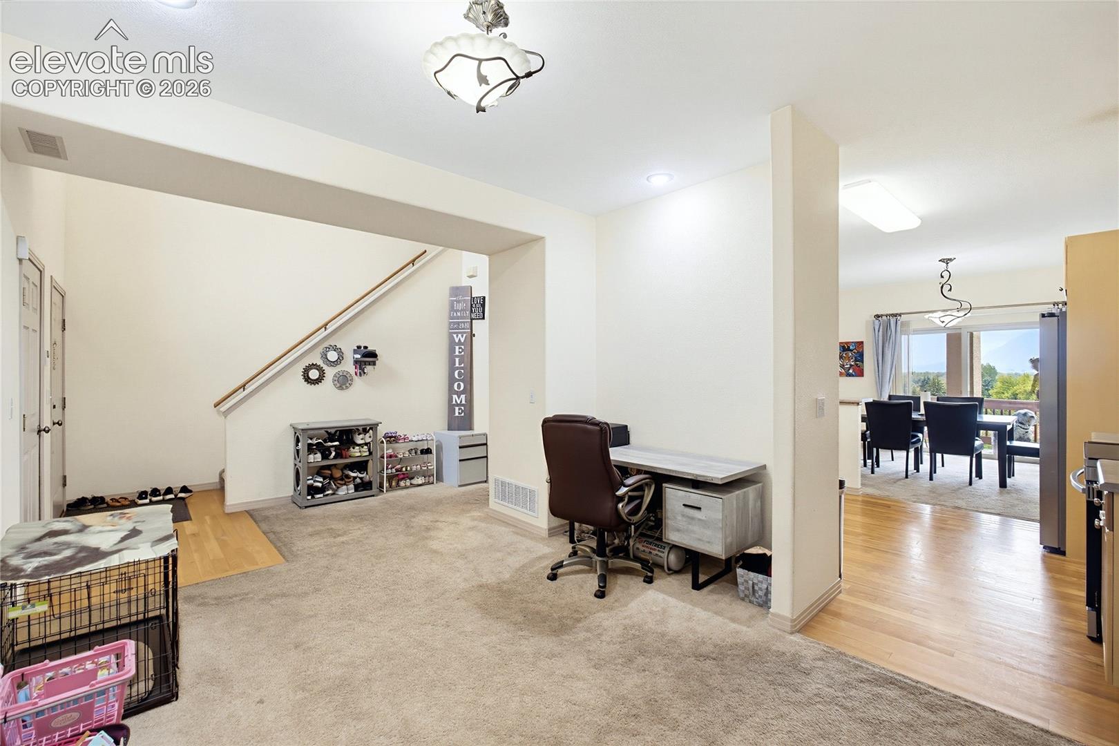 Carpeted living area with a staircase featuring a wood handrail, recessed lighting, and a chandelier