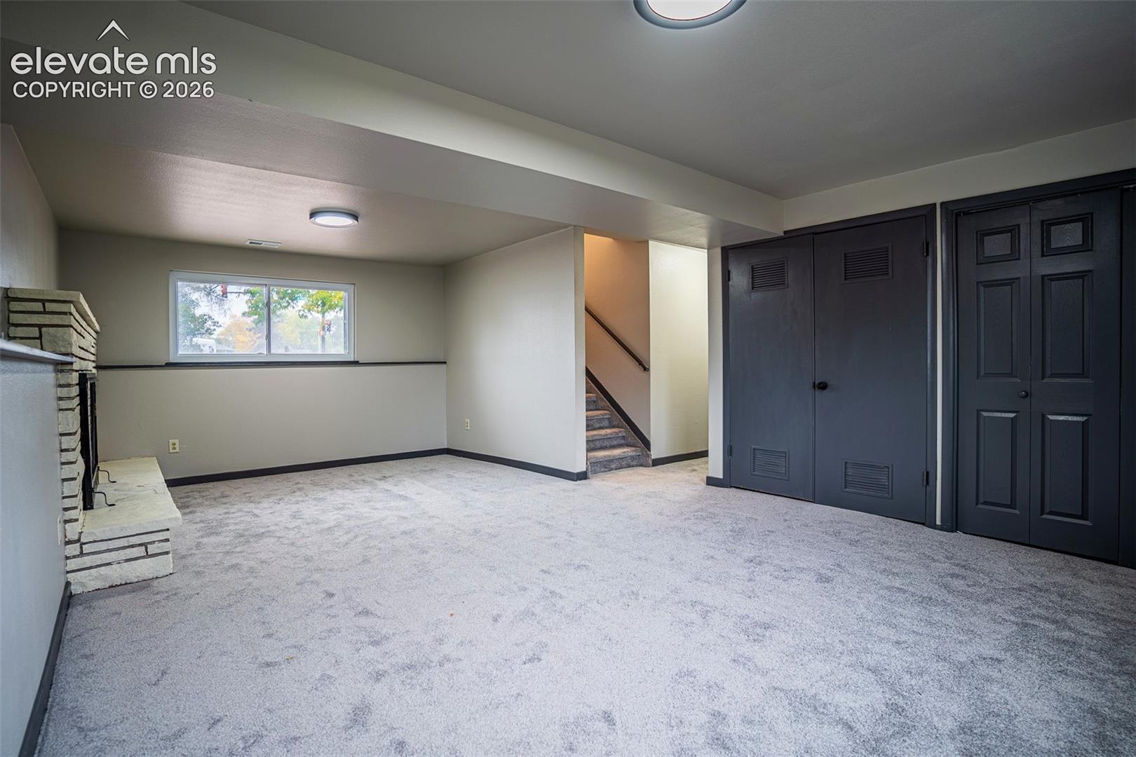 Stone-faced fireplace, neutral wall-to-wall carpeting, recessed ceiling lighting, and dual-panel closet doors