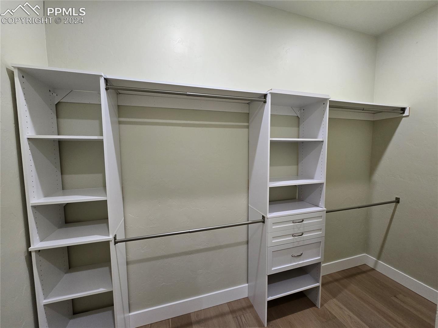 Spacious closet with dark hardwood / wood-style floors