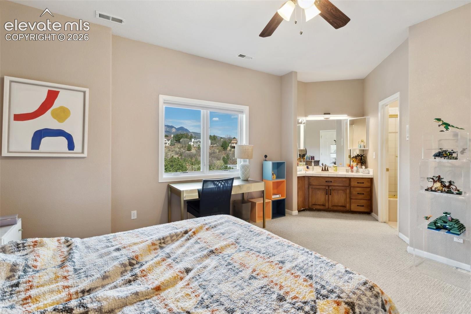 Bedroom featuring a window with a mountain backdrop, a ceiling fan, and light-colored carpeting