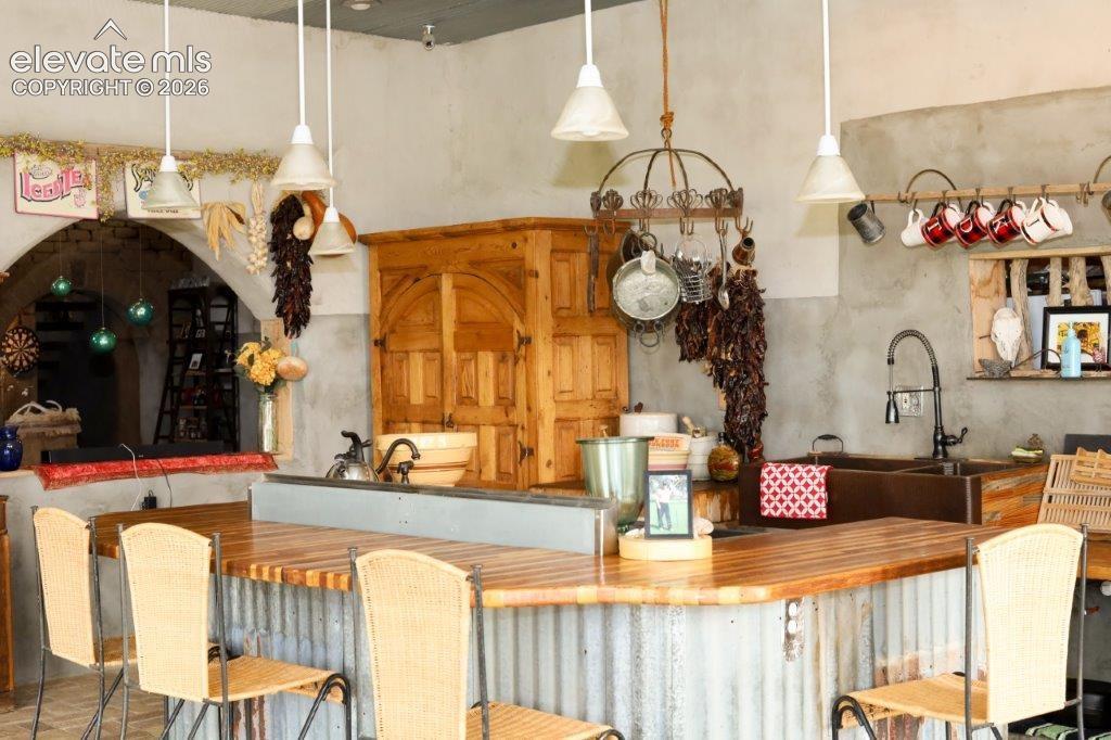 Kitchen featuring a corrugated metal breakfast bar with a wood-finish countertop, a double basin sink with a dark faucet, and a built-in wooden cabinet