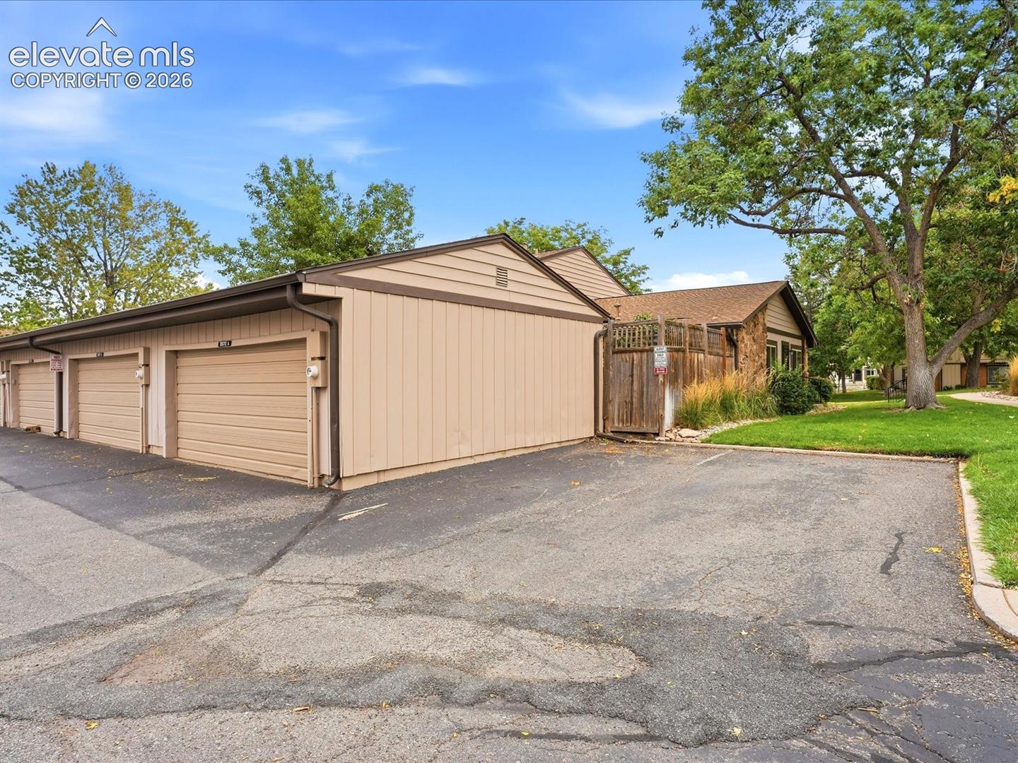 Multi-car garage featuring vertical wood siding, asphalt parking area, and wood privacy fencing