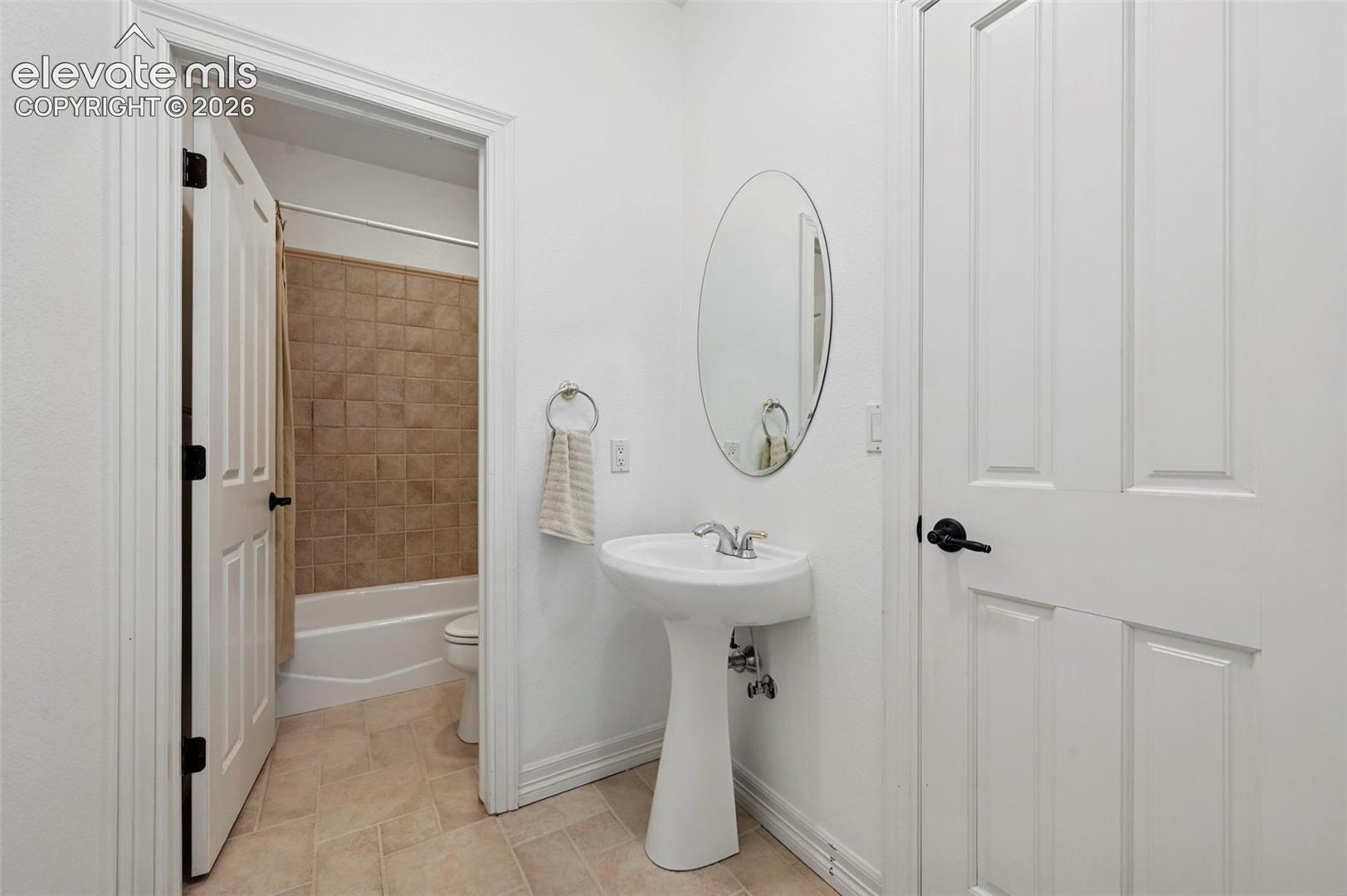 Pedestal sink with oval mirror and polished chrome faucet