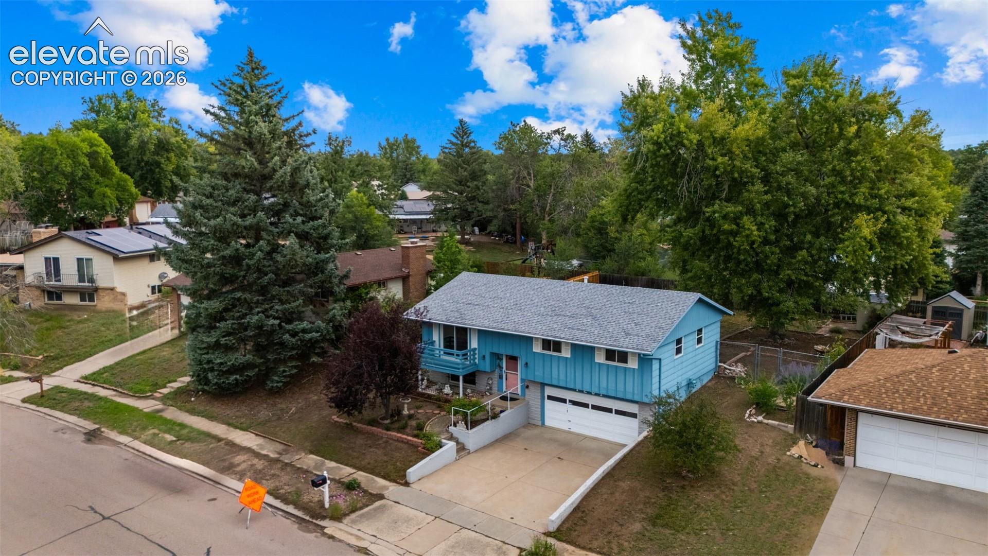 Split-level residence featuring a two-car garage, established landscaping, and a sloped driveway