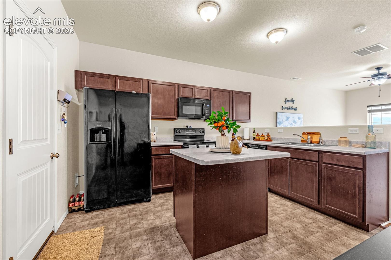 Kitchen featuring a built-in island, dark wood-finish cabinetry, and black appliances