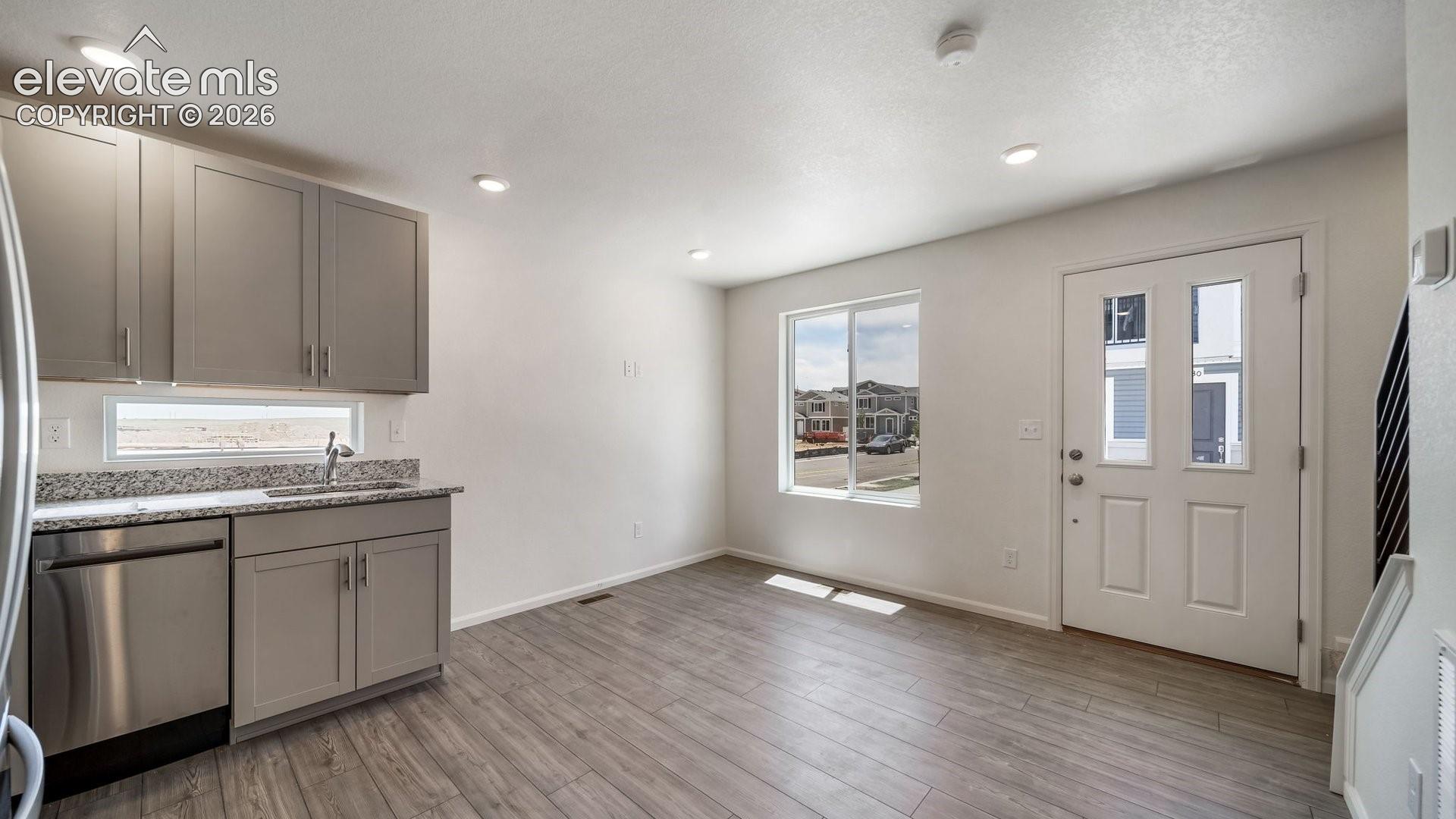 Contemporary kitchen featuring gray cabinetry, stainless steel dishwasher, speckled countertop, and a stainless steel sink with a chrome faucet
*photos of a model home*