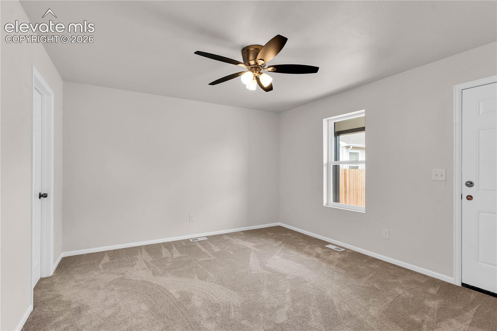 Neutral wall tones, wall-to-wall carpeting, and a multi-blade ceiling fan with integrated lighting