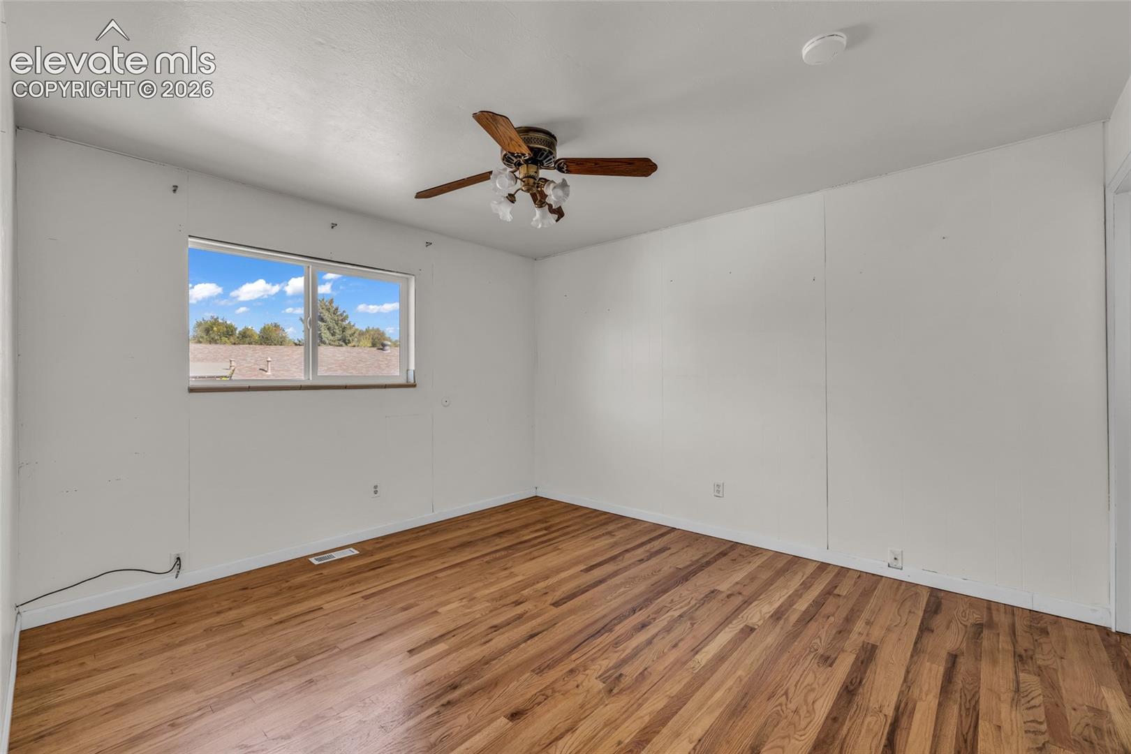 Hardwood flooring, white walls, and a multi-pane window