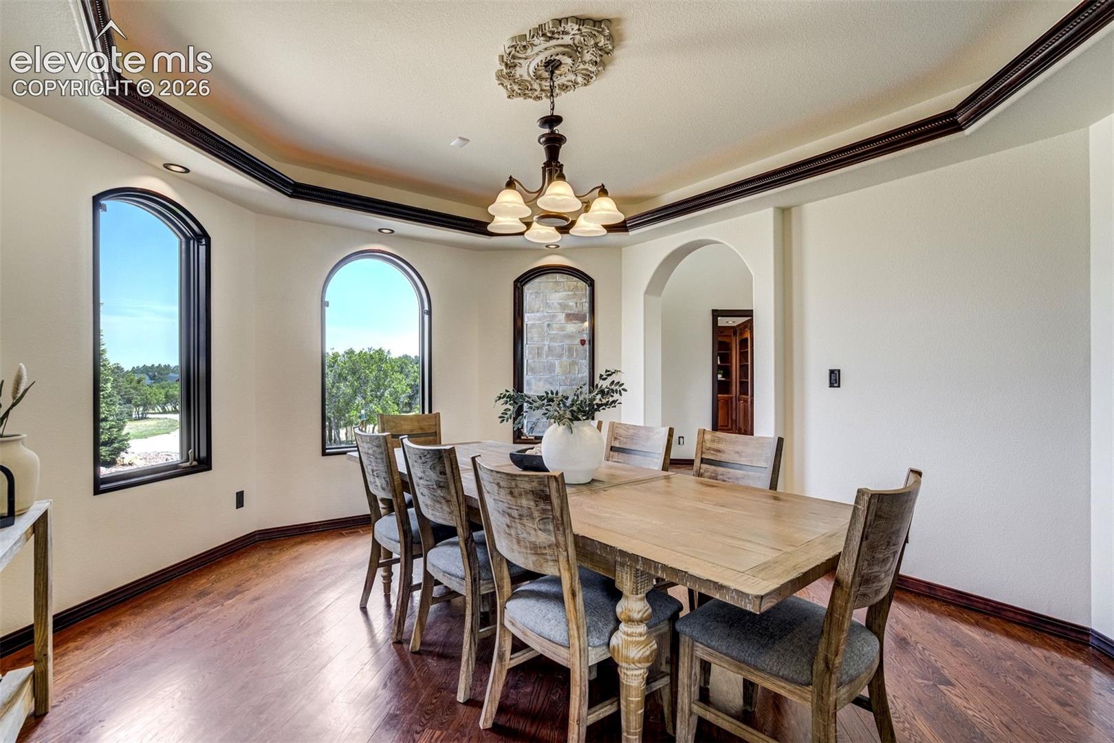 Formal dining space with arched windows & trace ceilings. 