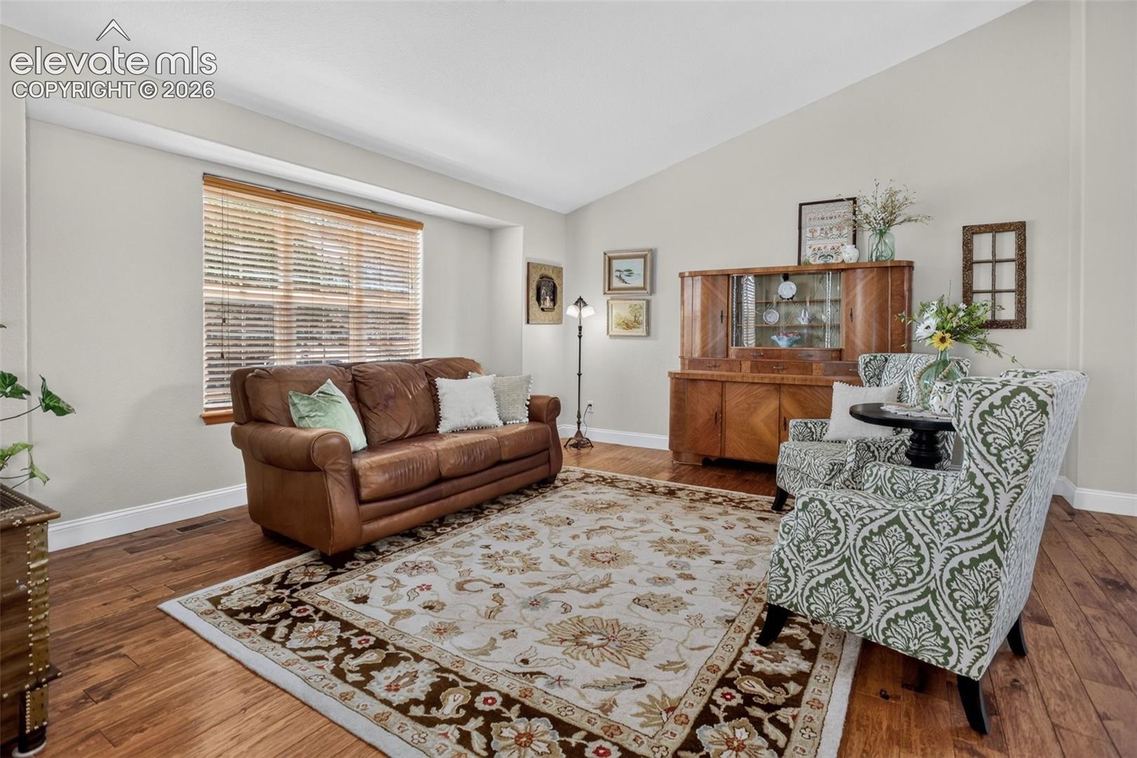 Spacious room featuring vaulted ceilings, wood-finish flooring, and light-toned walls