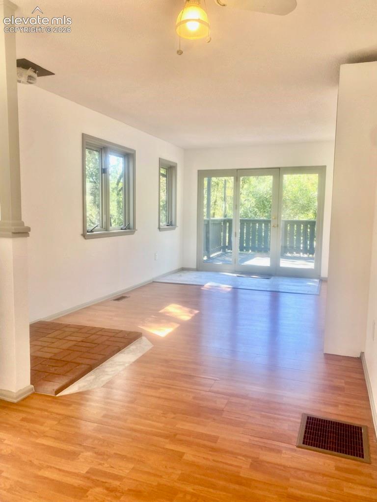 Wood-finish flooring throughout, brick fireplace hearth, and multiple windows