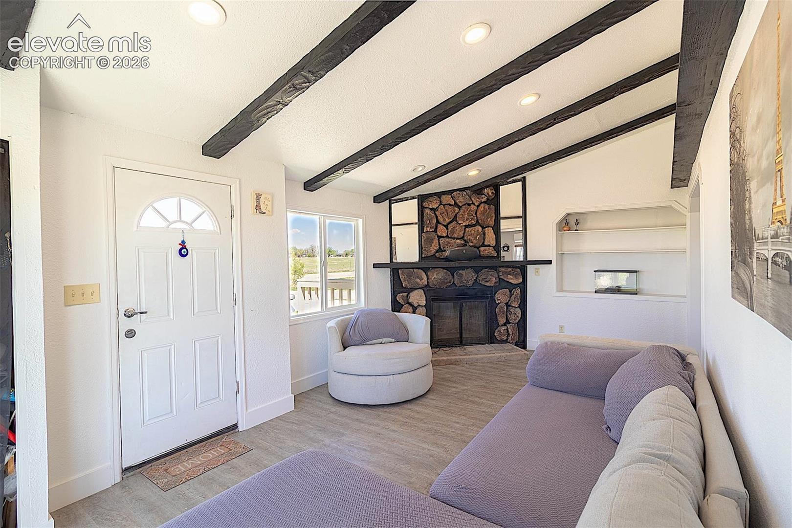 Living area with recessed lighting, a stone fireplace, wood finished floors, and baseboards