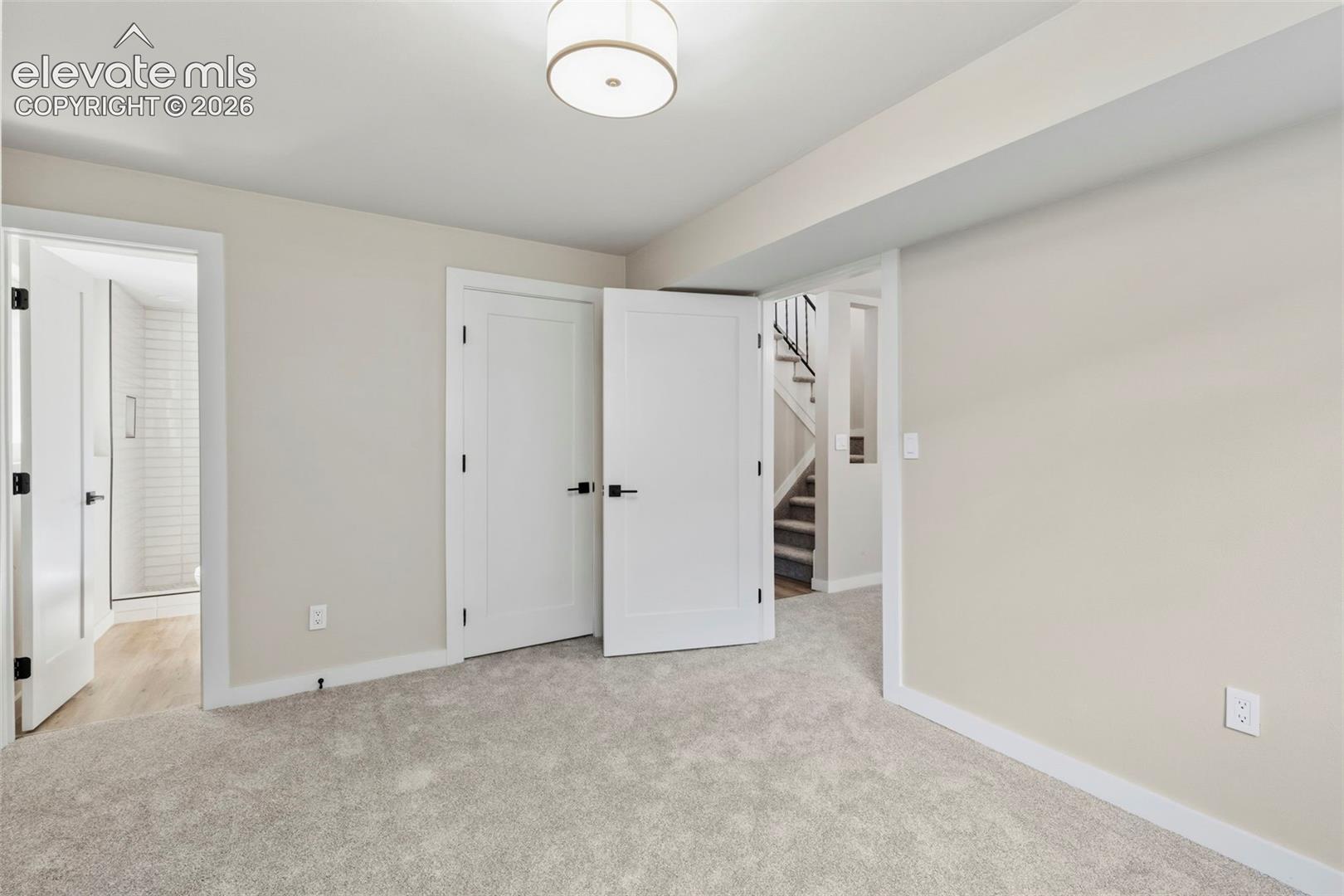 Carpeted room featuring light neutral wall paint and a flush-mount ceiling light fixture