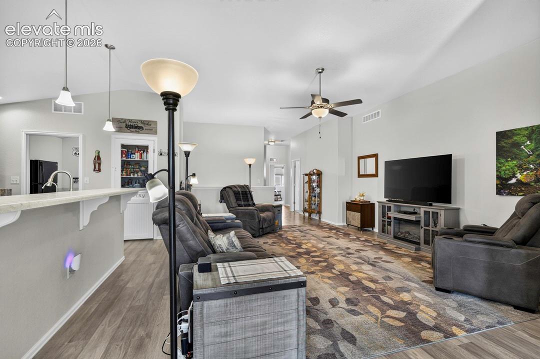 Vaulted ceilings enhance the main living area, featuring wood-finish flooring and a ceiling fan