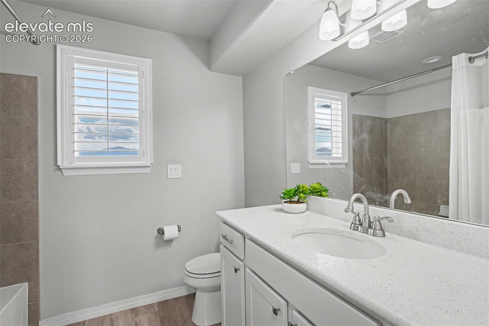 White vanity with a light speckled countertop, dual-handle chrome faucet, and integrated sink