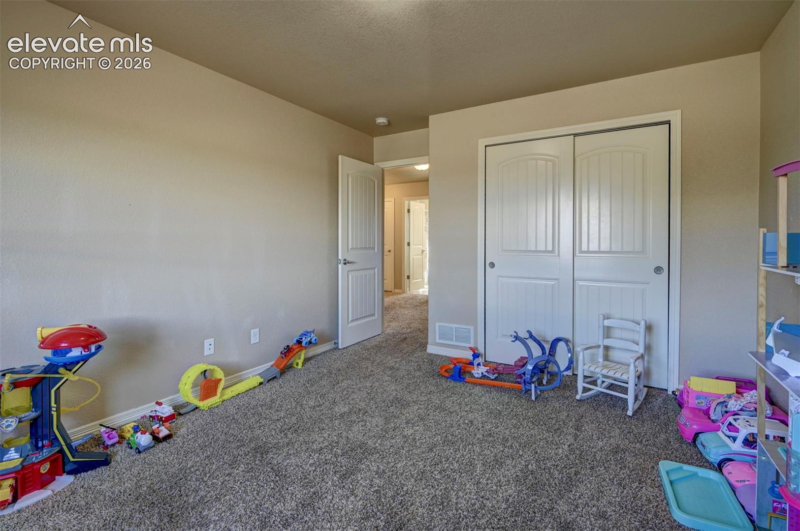 Neutral wall paint, carpet flooring, interior door with brushed nickel hardware, and bi-fold closet doors