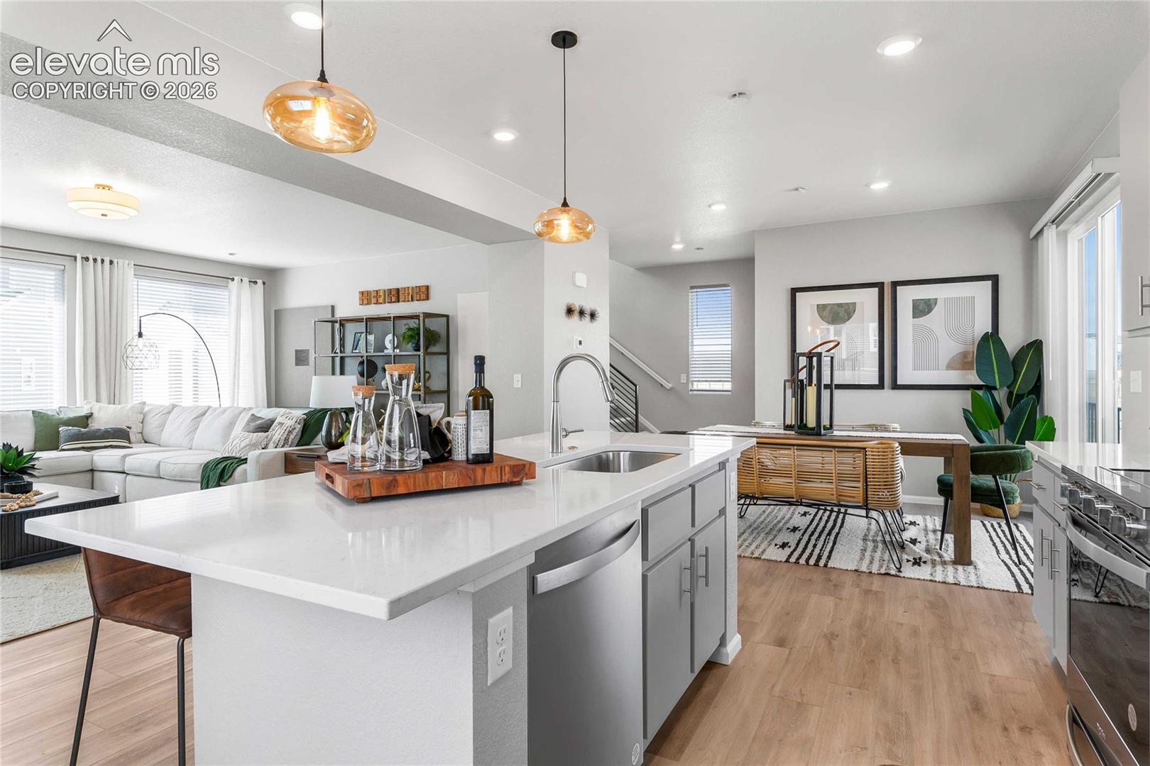 Open-concept living space featuring wood-finish flooring, a kitchen island with stone countertop, stainless steel appliances, and abundant natural light
*photos of a model home*