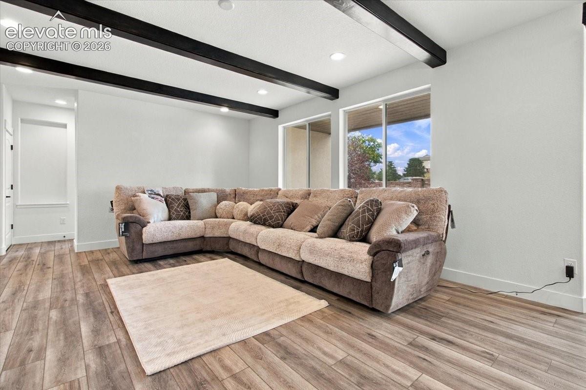 Interior space featuring exposed dark-finish ceiling beams, recessed lighting, wood-finish flooring, and large sliding glass doors