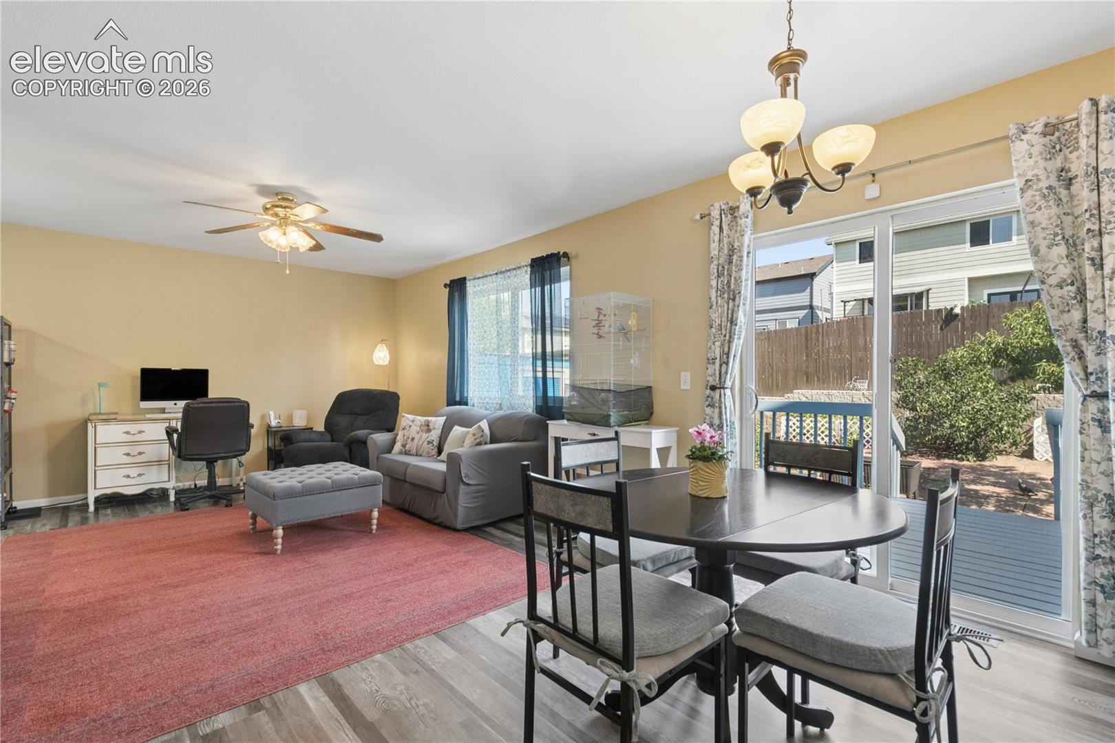Wood-finish flooring throughout, ceiling fan with integrated lighting, and a dining area with a chandelier