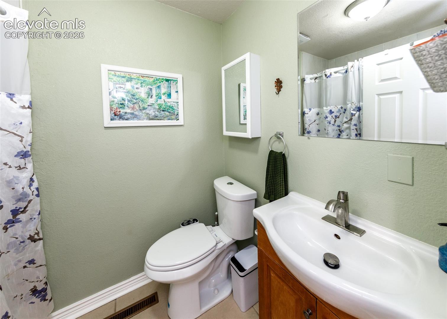 Bathroom featuring a built-in wood-finish vanity, integrated sink, and wall-mounted mirror