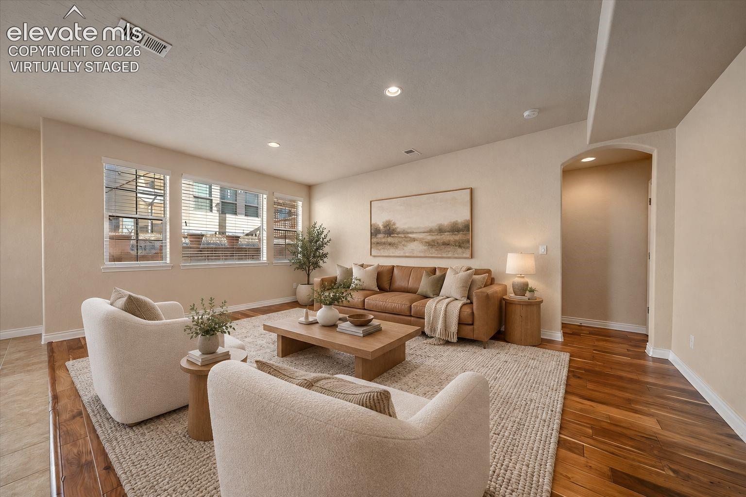 Virtually Staged. Living space featuring wood-finish flooring, recessed lighting, and a neutral color palette with a prominent arched doorway