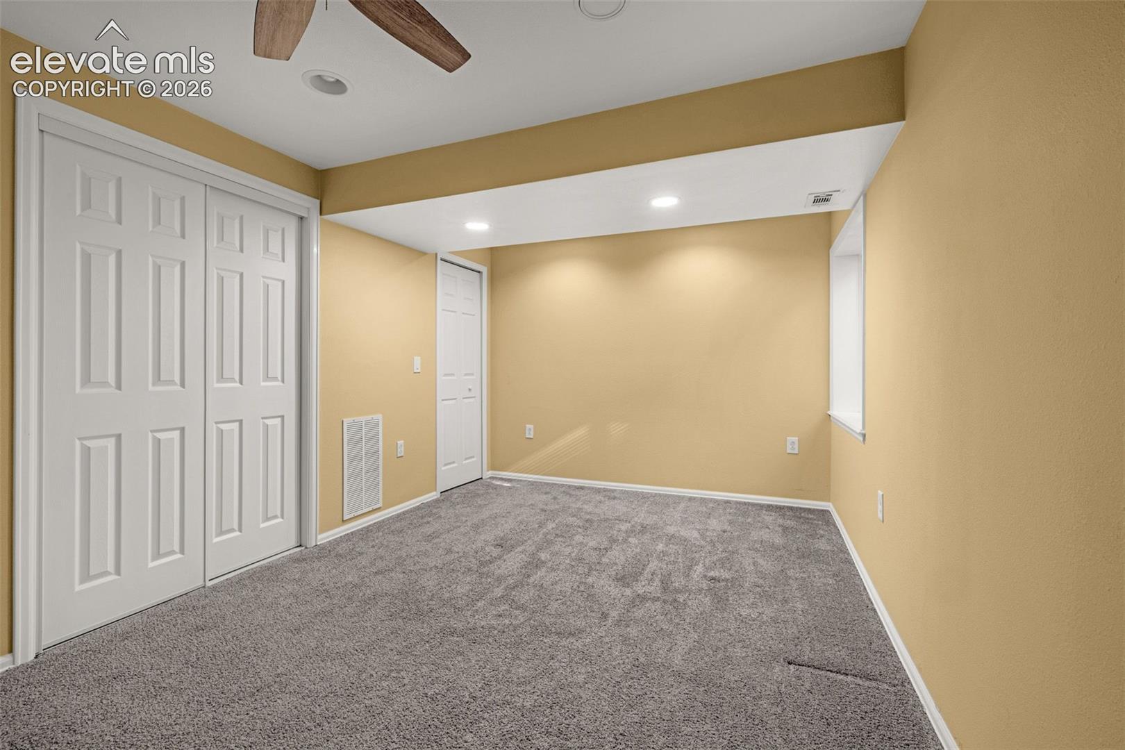 Interior space featuring wall-to-wall carpeting, recessed ceiling lighting, a ceiling fan, dual-panel sliding closet doors, and a single-panel interior door
