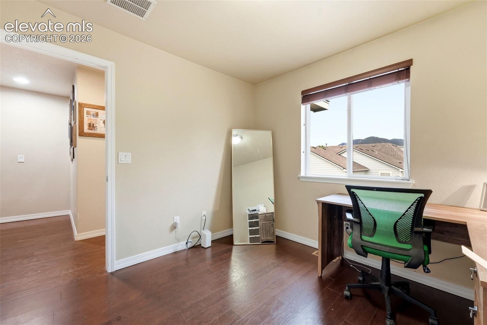 Dark wood-finish flooring, neutral wall paint, white trim, and a window with mountain scenery