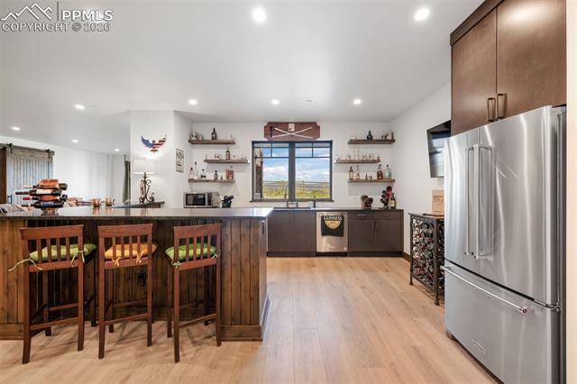 Wet bar with seating, fridge, dishwasher, and ice maker.