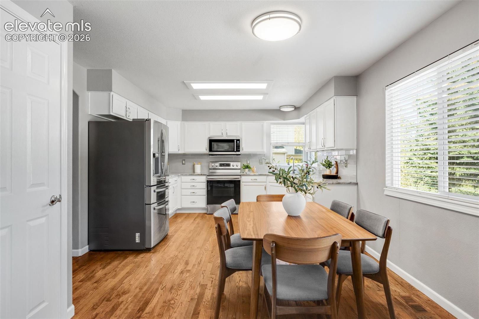 Kitchen featuring white cabinetry, stainless steel appliances, wood-finish flooring, and recessed ceiling lighting