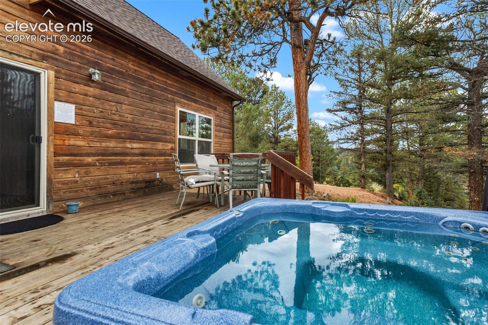 Private deck with a built-in hot tub, offering an outdoor dining area, wood-plank siding, and a gabled roofline