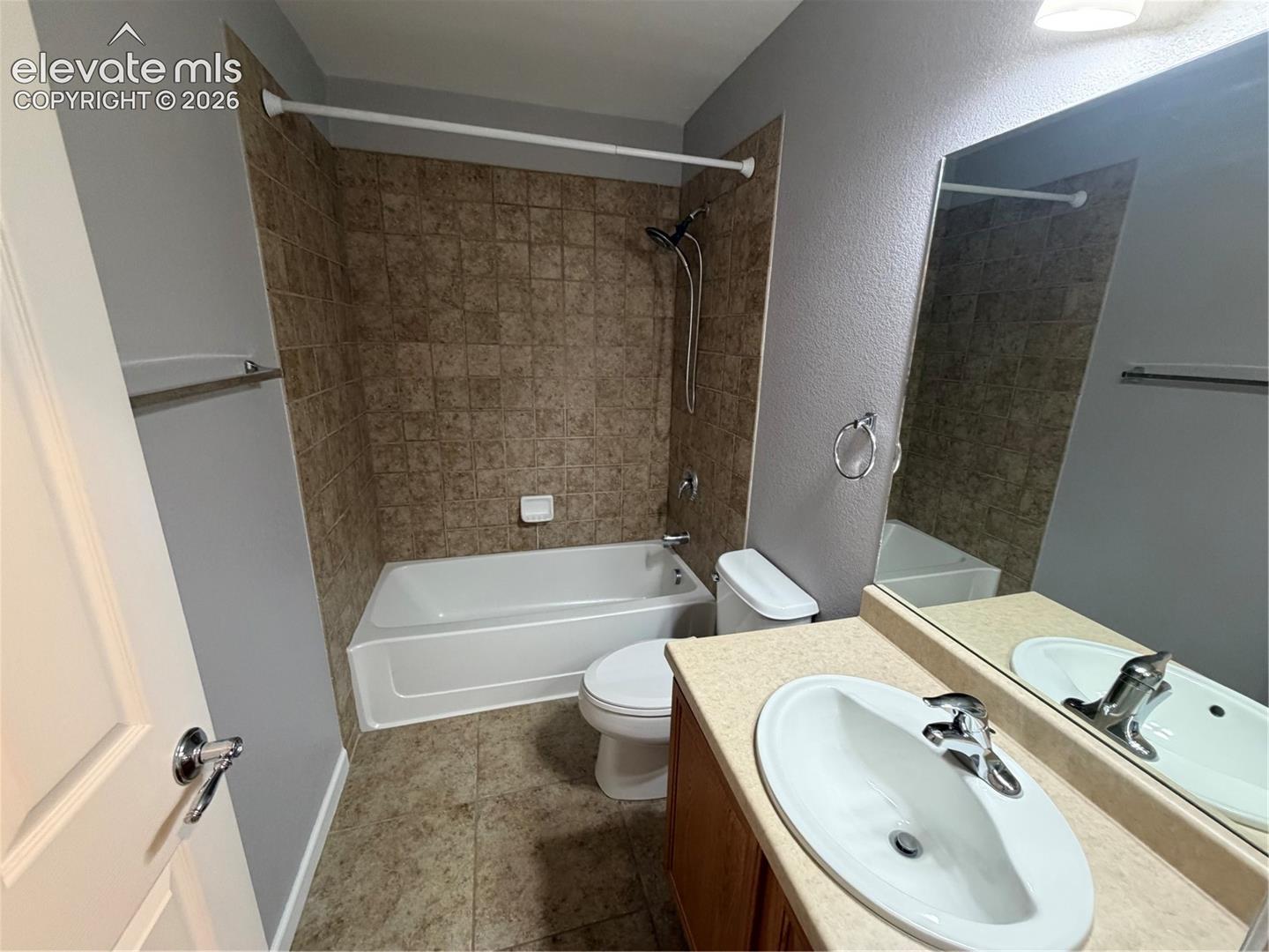 Bathroom featuring a white bathtub, ceramic tile surround, integrated vanity sink, and a framed mirror