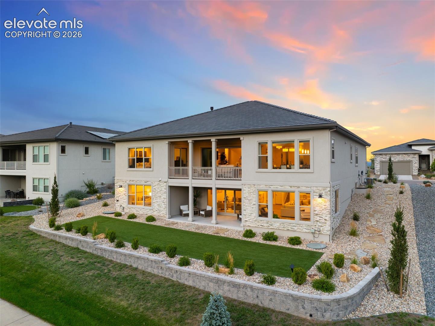 Stucco exterior with stone accents, a covered balcony, and a covered patio.  Low maintenance , irrigated landscaping