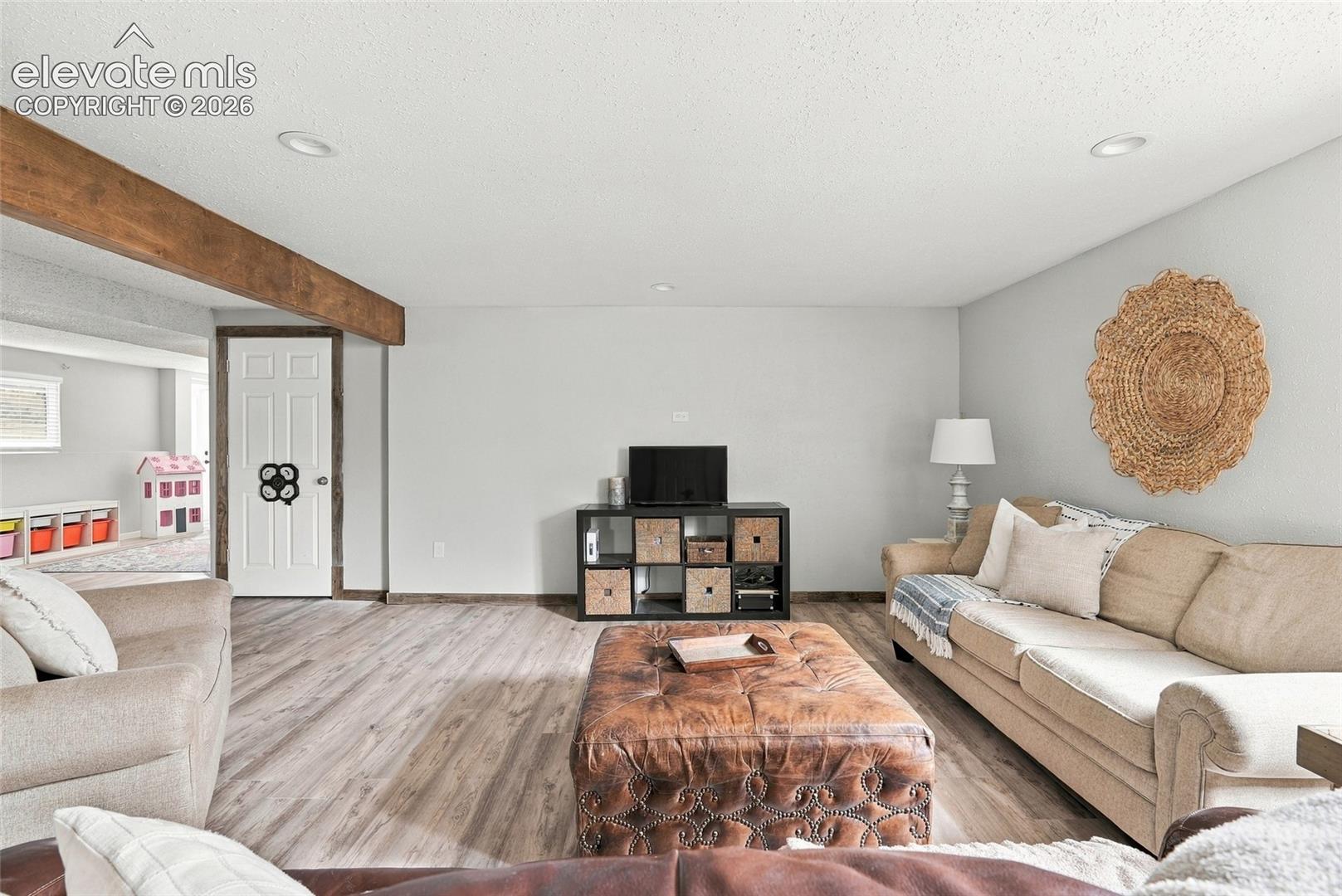 Wood-finish flooring, recessed lighting, exposed beam, and white interior doors
