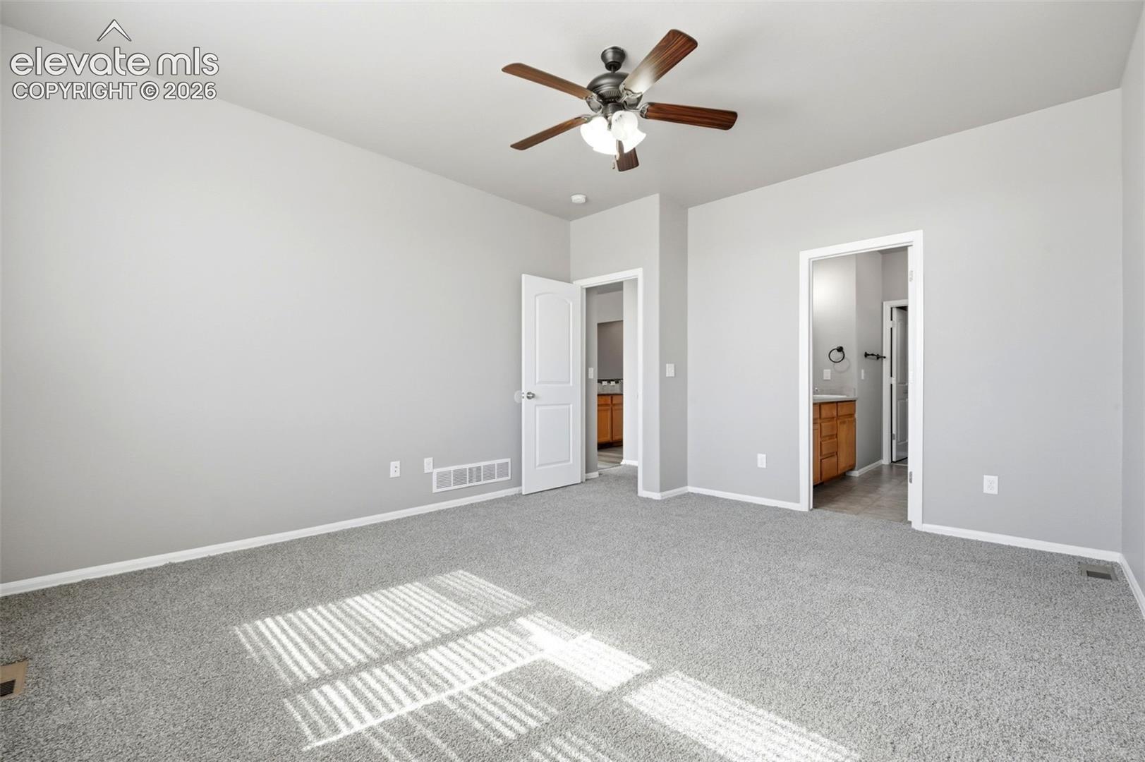Ceiling fan with wooden blades, light gray wall paint, and gray carpeting