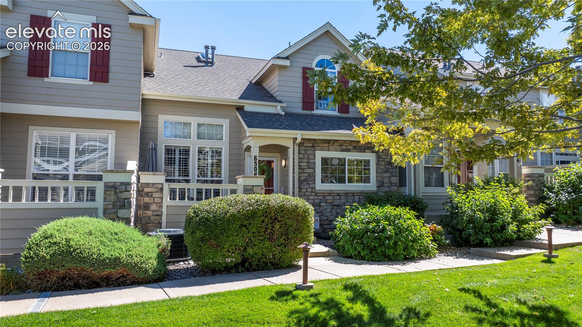 Multi-level exterior featuring horizontal lap siding, stacked stone veneer accents, arched window detailing, and decorative shutters