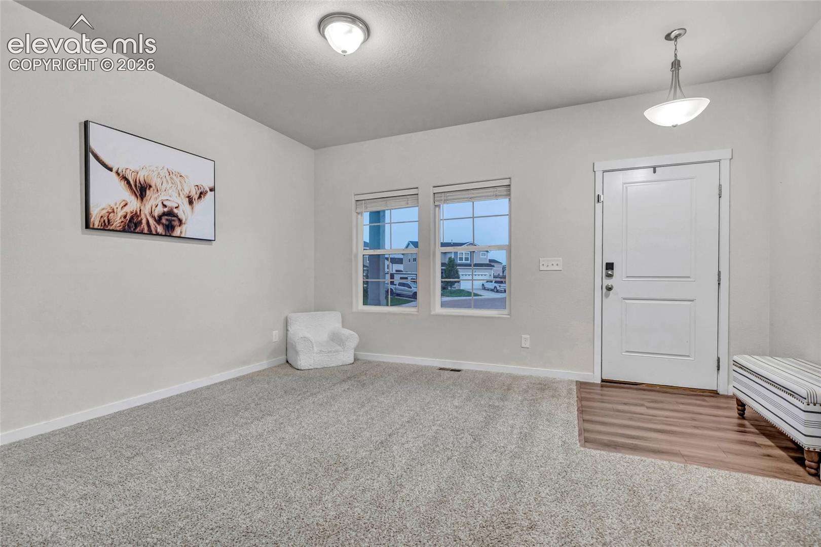 Entry area featuring wood-finish flooring, a white paneled door, and two windows