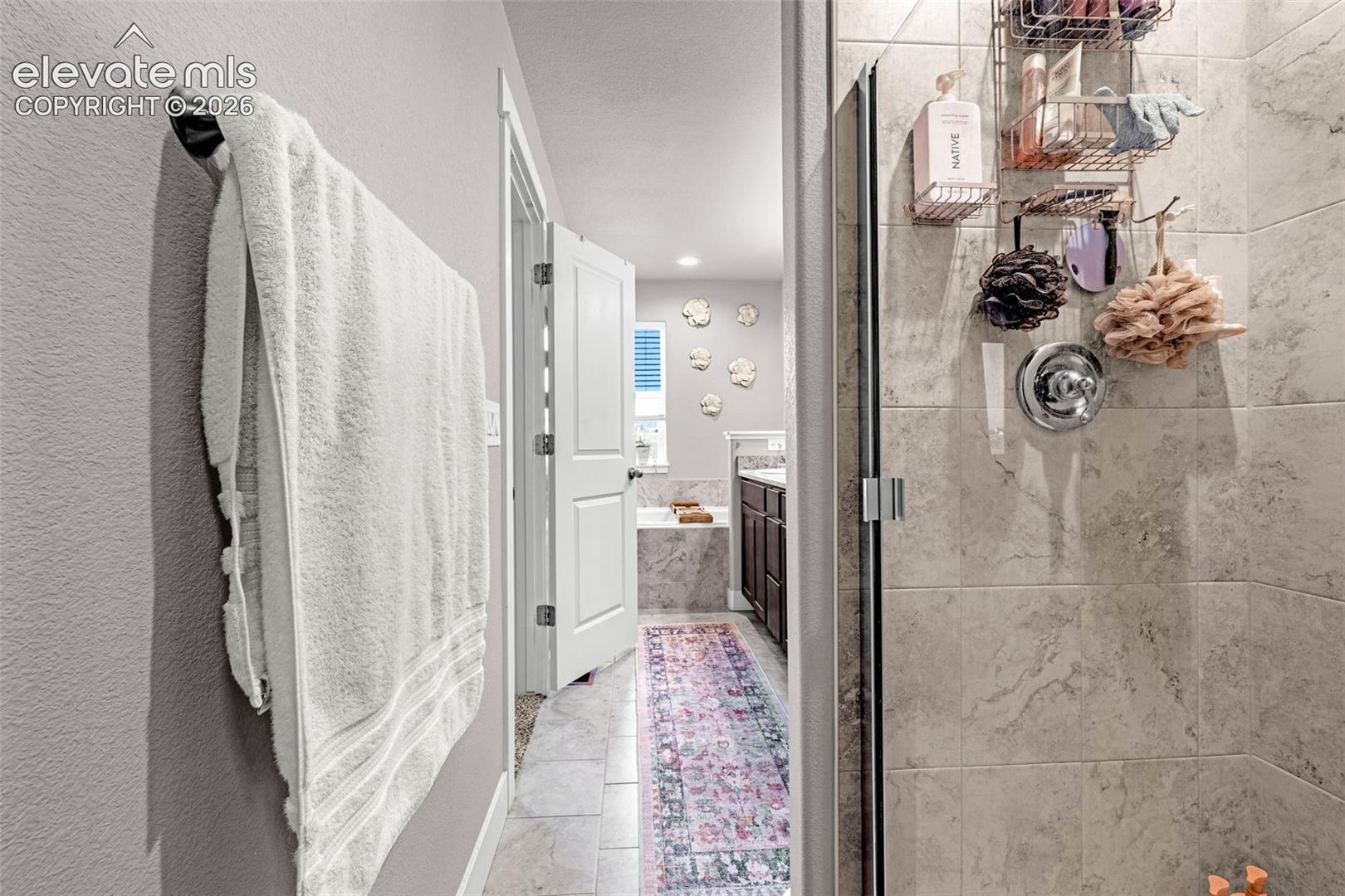Glass-enclosed shower with large format tile surround and chrome fixtures