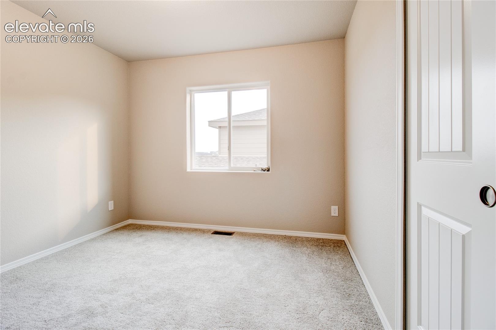 Neutral interior space featuring wall-to-wall carpeting, light-toned wall paint, a sliding window with a white frame, and a multi-panel door