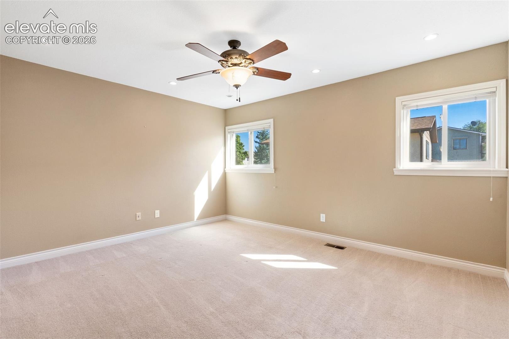 Room featuring neutral wall tones, wall-to-wall carpeting, recessed ceiling lighting, and a multi-blade ceiling fan with an integrated light fixture