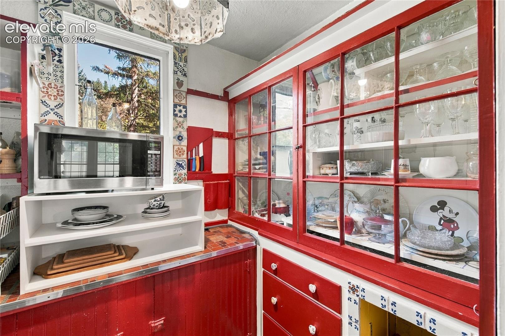 Large walk-in pantry with beautiful glass door cabinets and storage. Enjoy the tile accents and unique chandeliers