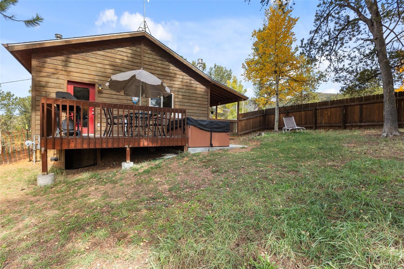 Wood-sided exterior featuring an elevated deck with a hot tub and a private fenced yard