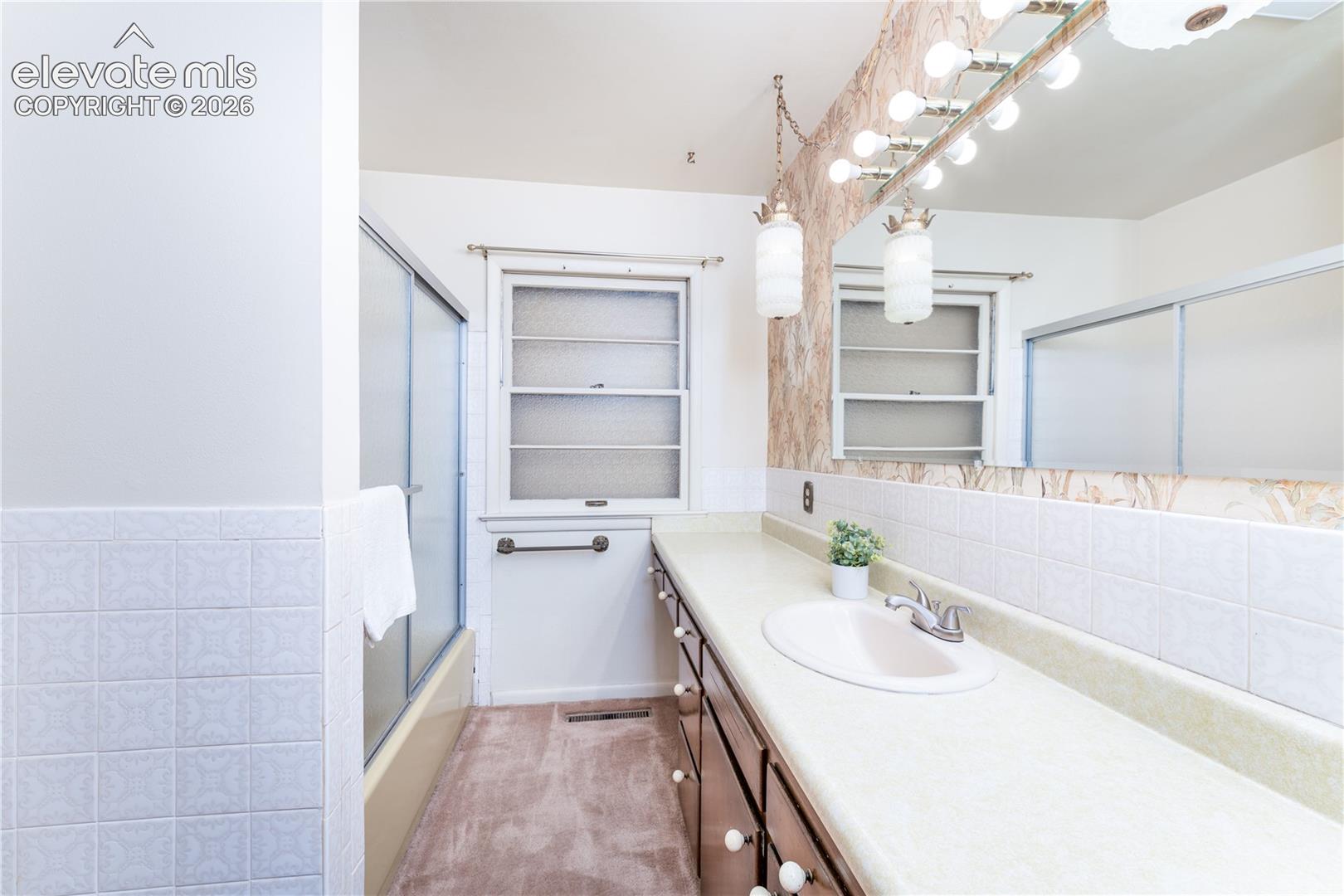 Extended vanity with integrated sink, full-width mirror, and multi-bulb vanity lighting