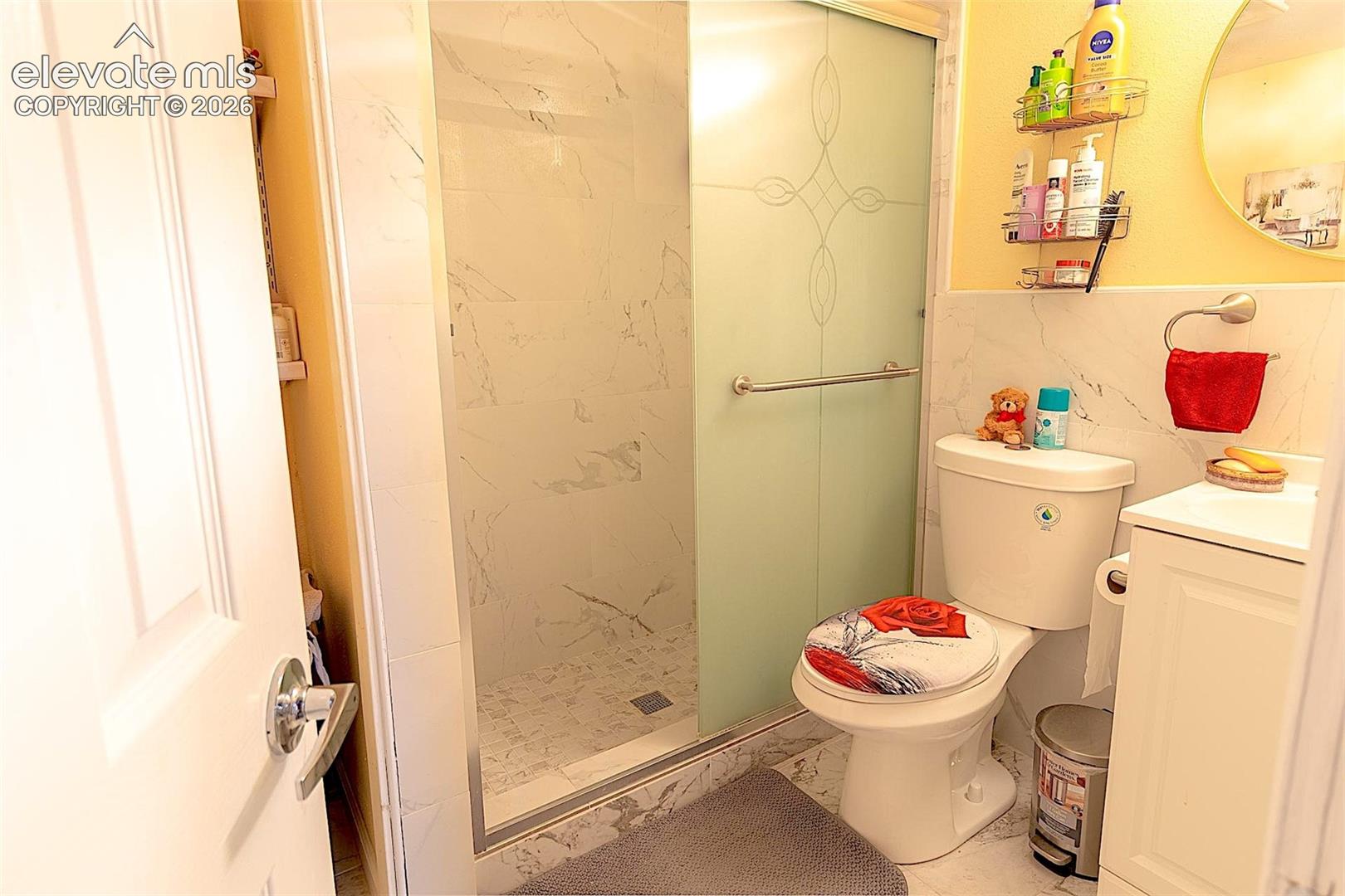 Full bathroom featuring marble finish floors, vanity, toilet, and a shower stall