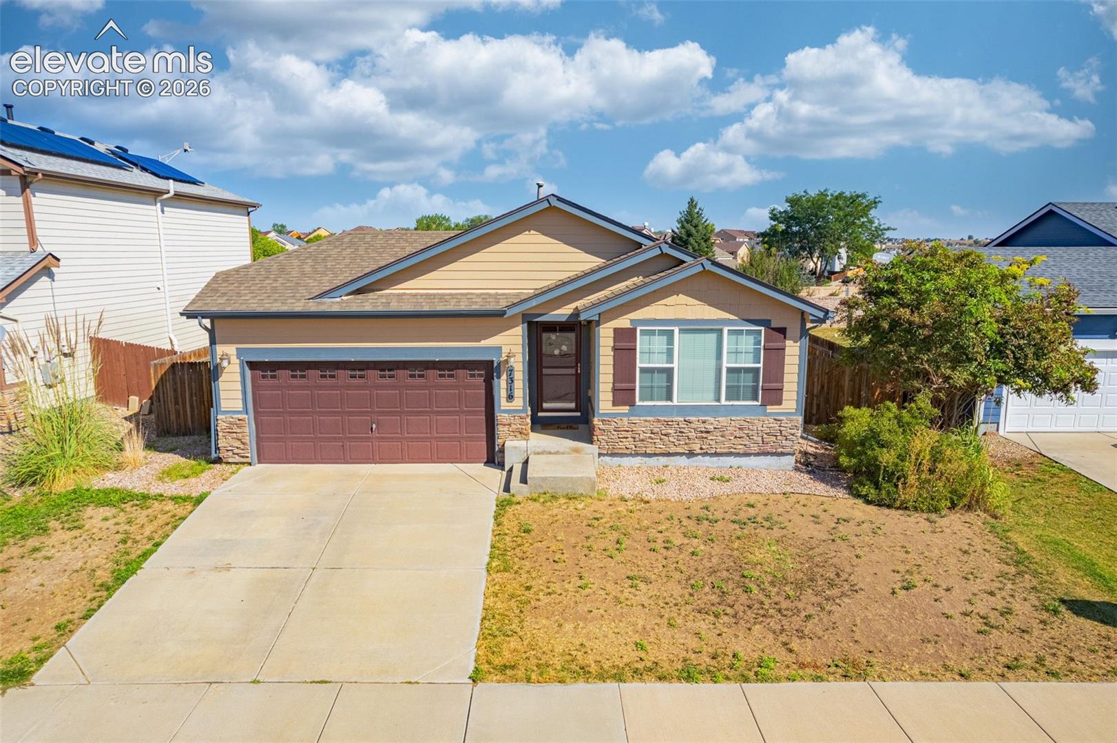 Single-story residence featuring a two-car garage, stone veneer accents, and a front entry with a transom window
