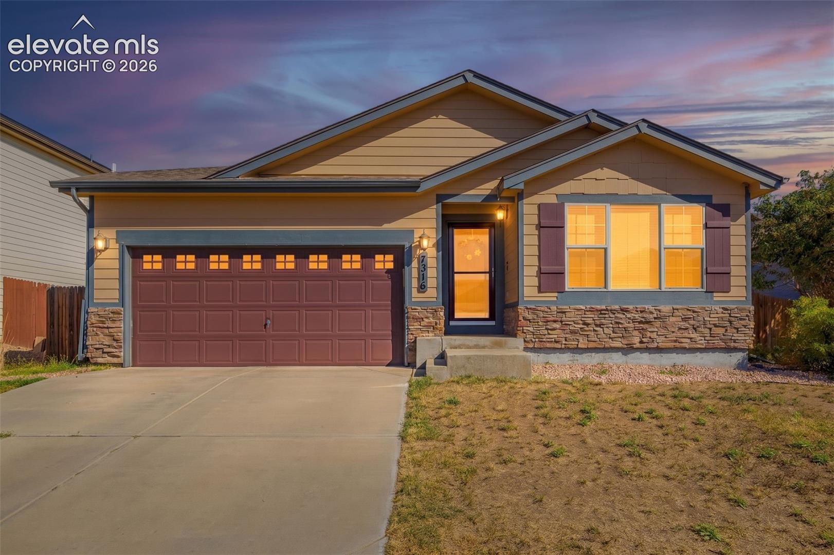 Single-story residence featuring a two-car garage with transom windows, a concrete driveway, and stone veneer accents